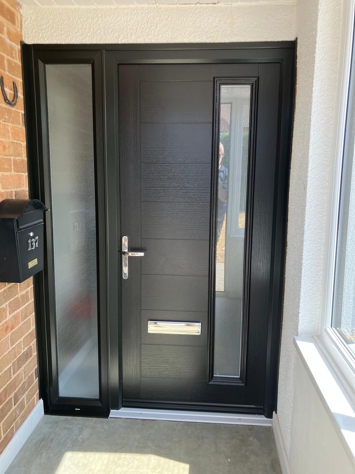 Black composite front door with tall vertical glazing and a frosted side panel