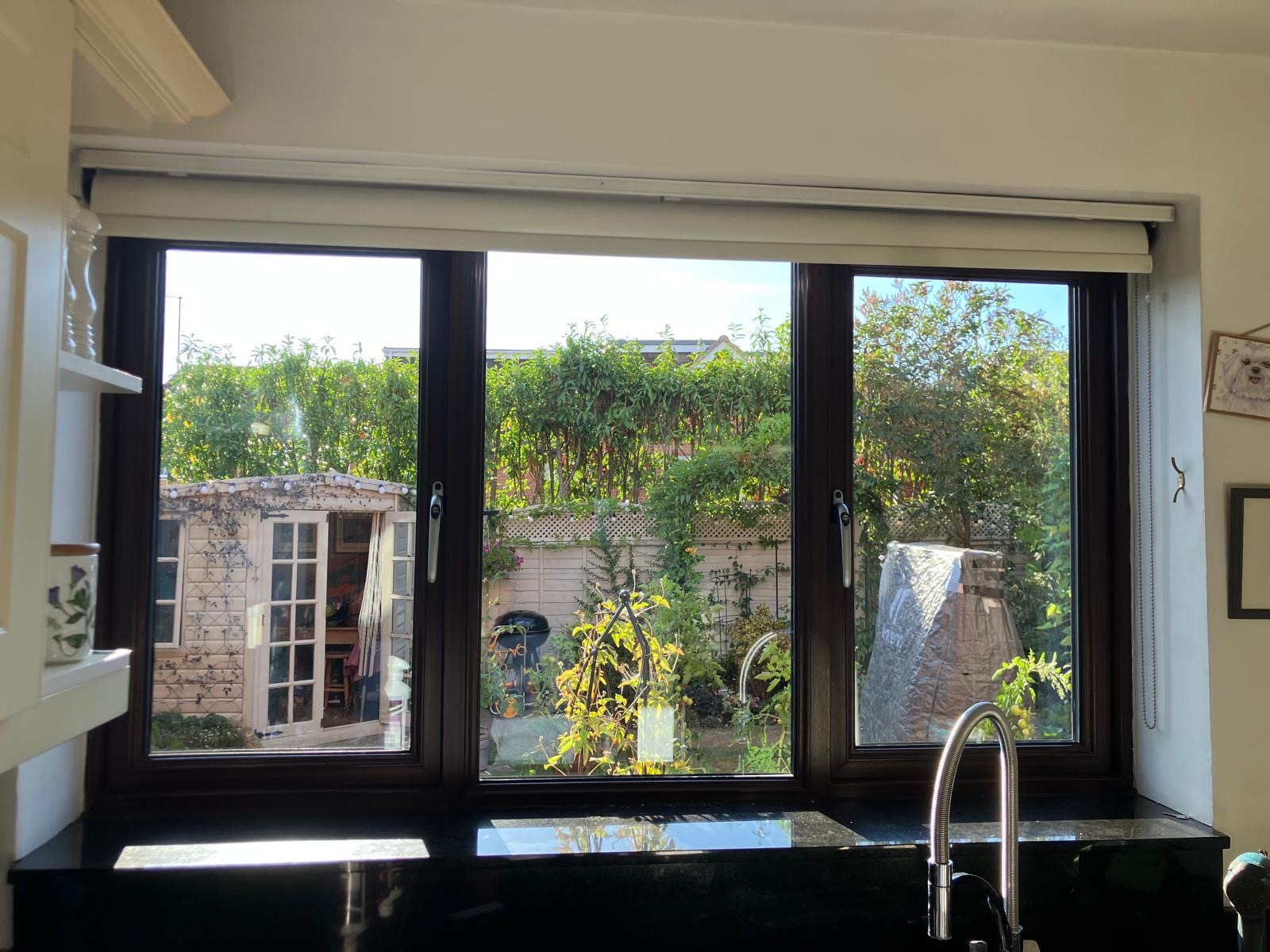 Refurbished dark-framed kitchen window overlooking a garden